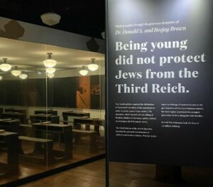 Photo of empty German classroom and sign that says being young did not protect Jews from the Third Reich.